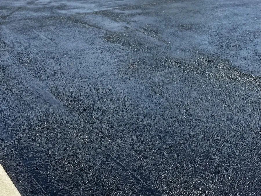Freshly sealcoated residential driveway with a deep black finish